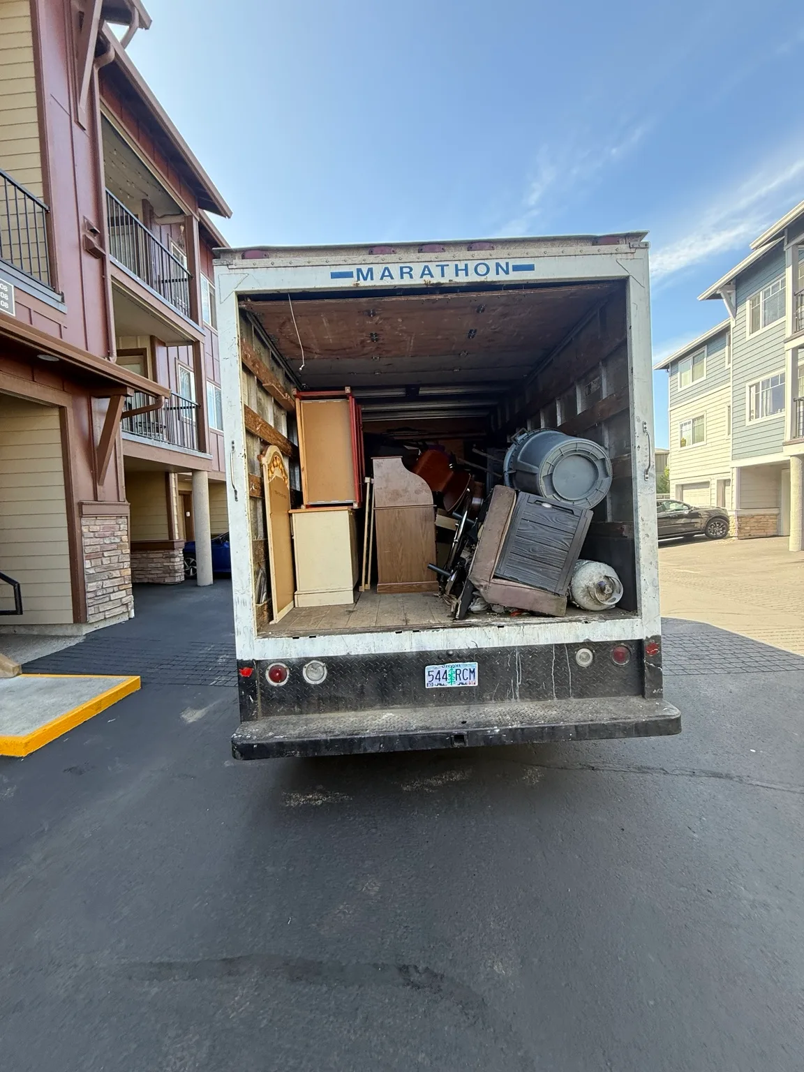 Furniture and household items loaded into a JunkPDX truck outside an apartment building