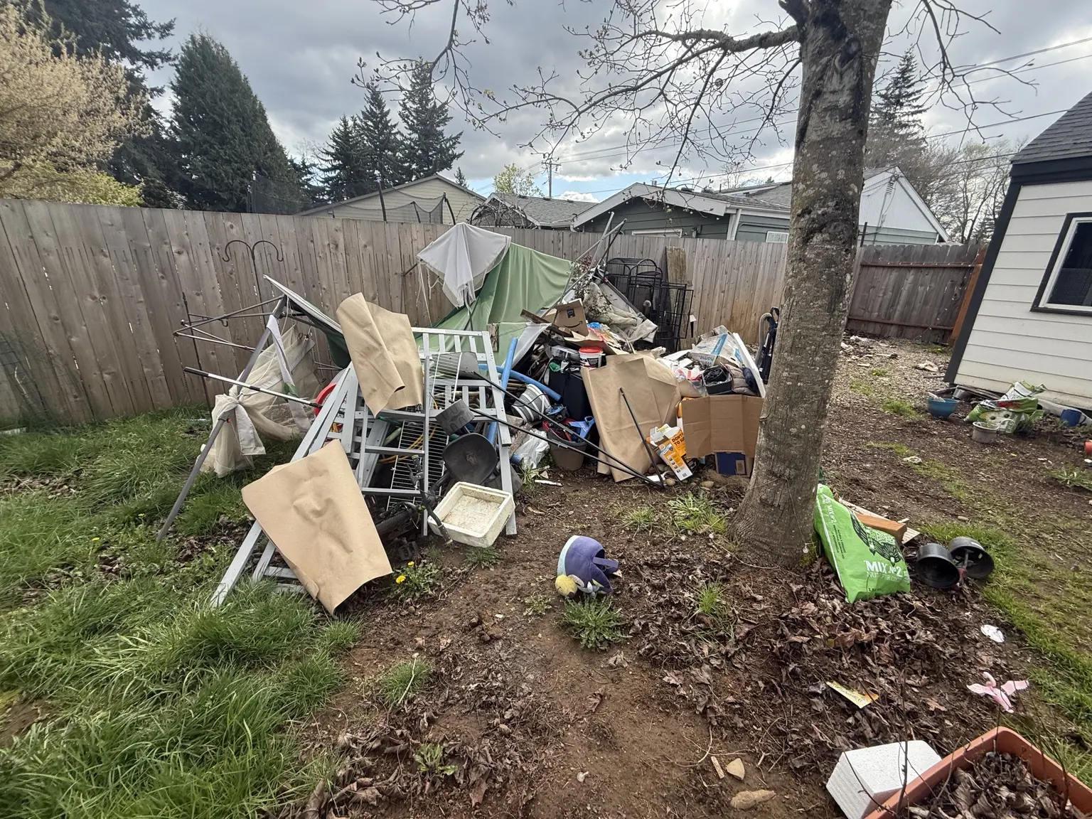 Metal frames, boxes and household contents outside before a documented JunkPDX removal