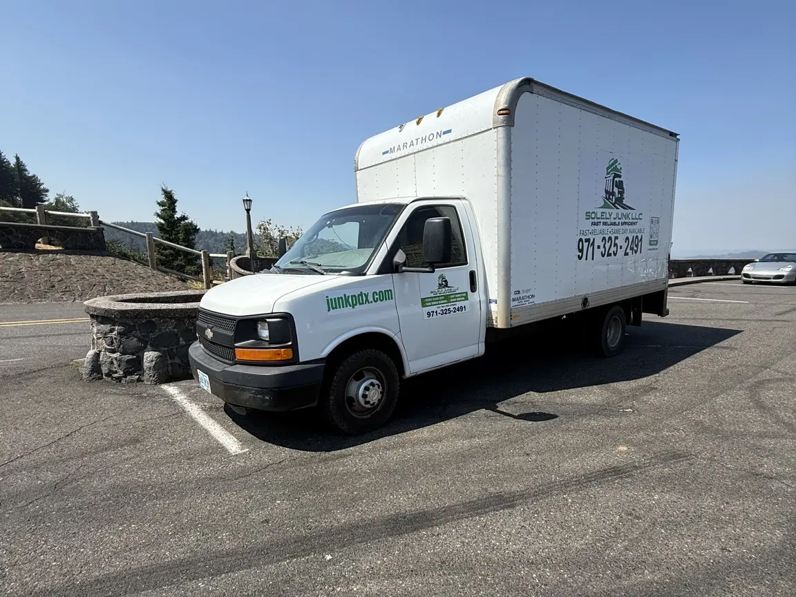 White JunkPDX box truck with green junkpdx.com branding on the cab and company details on the side