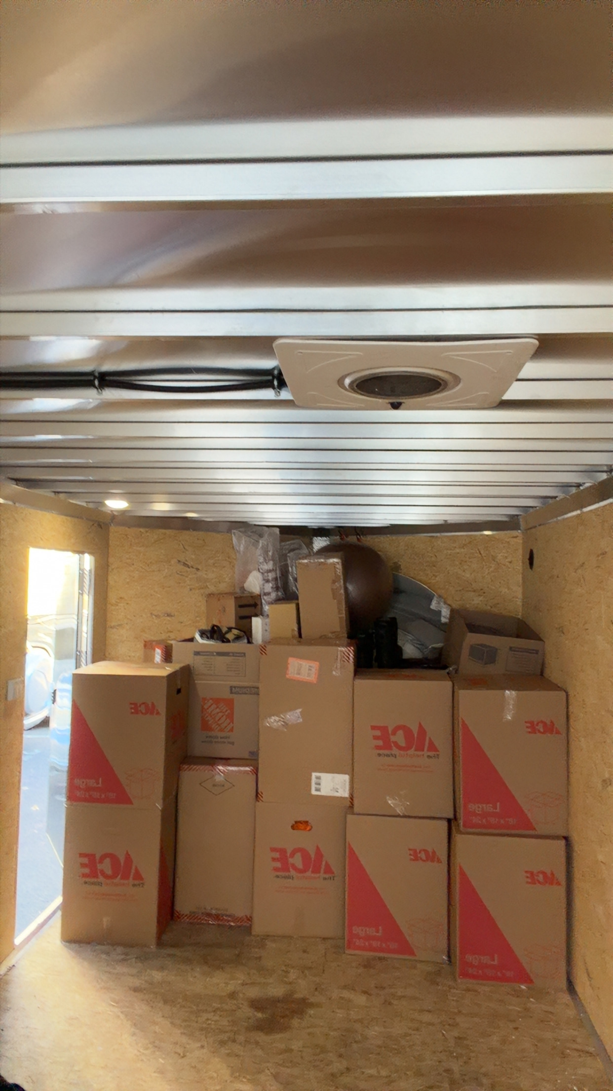 Moving boxes and household items stacked inside an enclosed trailer